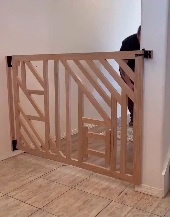Wooden pet gate installed in doorway with a cat visible behind it, watching through the gap