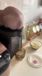Brown cat with head stuck in a coffee maker on a kitchen counter with dishes and ingredients nearby