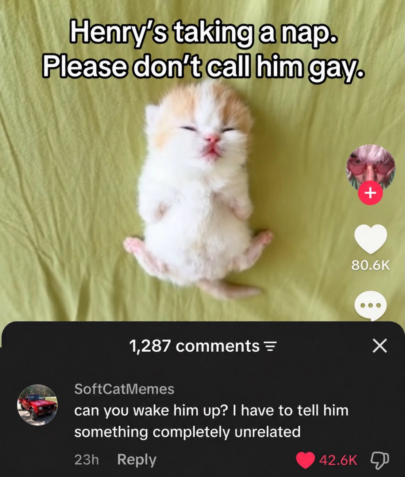 A tiny cream and white kitten napping peacefully on its back on a green blanket with eyes closed